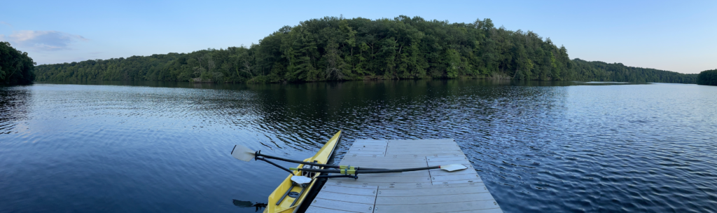rowing shell next to a dock with flat water
